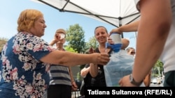 Apă potabilă, pusă la dispoziția trecătorilor la intersecția bulevardului Ștefan cel Mare și Sfânt cu strada Armenească, iulie 2024. Medicii recomandă hidratarea suficientă pe timp de caniculă.