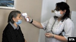 Медицински работник мери температурата на жена в дом за възрастни хора в Бургас