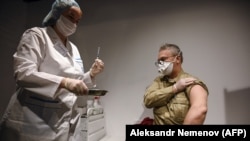 RUSSIA -- A man prepares to receive an injection of Russia's Sputnik V (Gam-COVID-Vac) vaccine against the coronavirus disease at a vaccination point at the GUM department store in Moscow, January 18, 2021