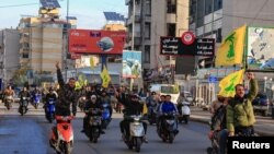 Bărbați care poartă steaguri Hezbollah în suburbiile sudice ale Beirutului, capitala Libanului, după un anunț al încetării focului între Israel și gruparea Hezbollah susținută de Iran a intrat în vigoare miercuri, 27 noiembrie 2024.