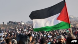 Një person duke valëvitur një flamur palestinez gjatë zhvendosjes së njerëzve në veriun e Rripit të Gazës. Fotografi nga arkivi.