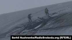 Ukrainian workers inspect damage to the Chernobyl nuclear power plant's confinement shelter after a Russian drone attack on February 14.