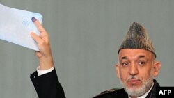 Afghan President Hamid Karzai gestures before casting his vote at a polling station in Kabul.