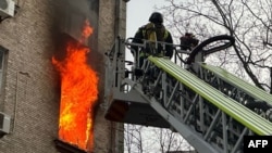 Un pompier ucrainean luptă cu un incendiu într-o clădire rezidențială declanșat de un atac aerian rusesc asupra Kievului. 1 ianuarie 2024.